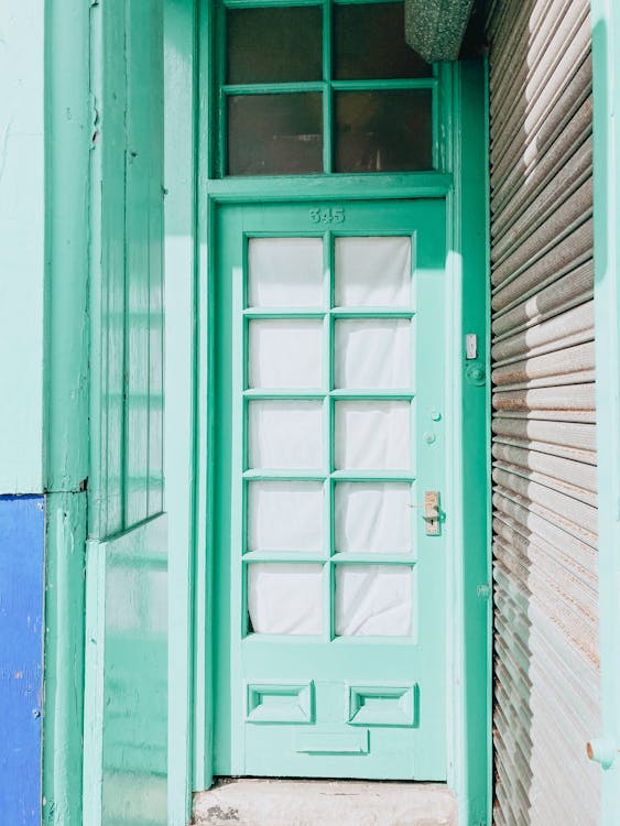 Free Exterior of old green wooden door with small curtained windows at sunny day Stock Photo
