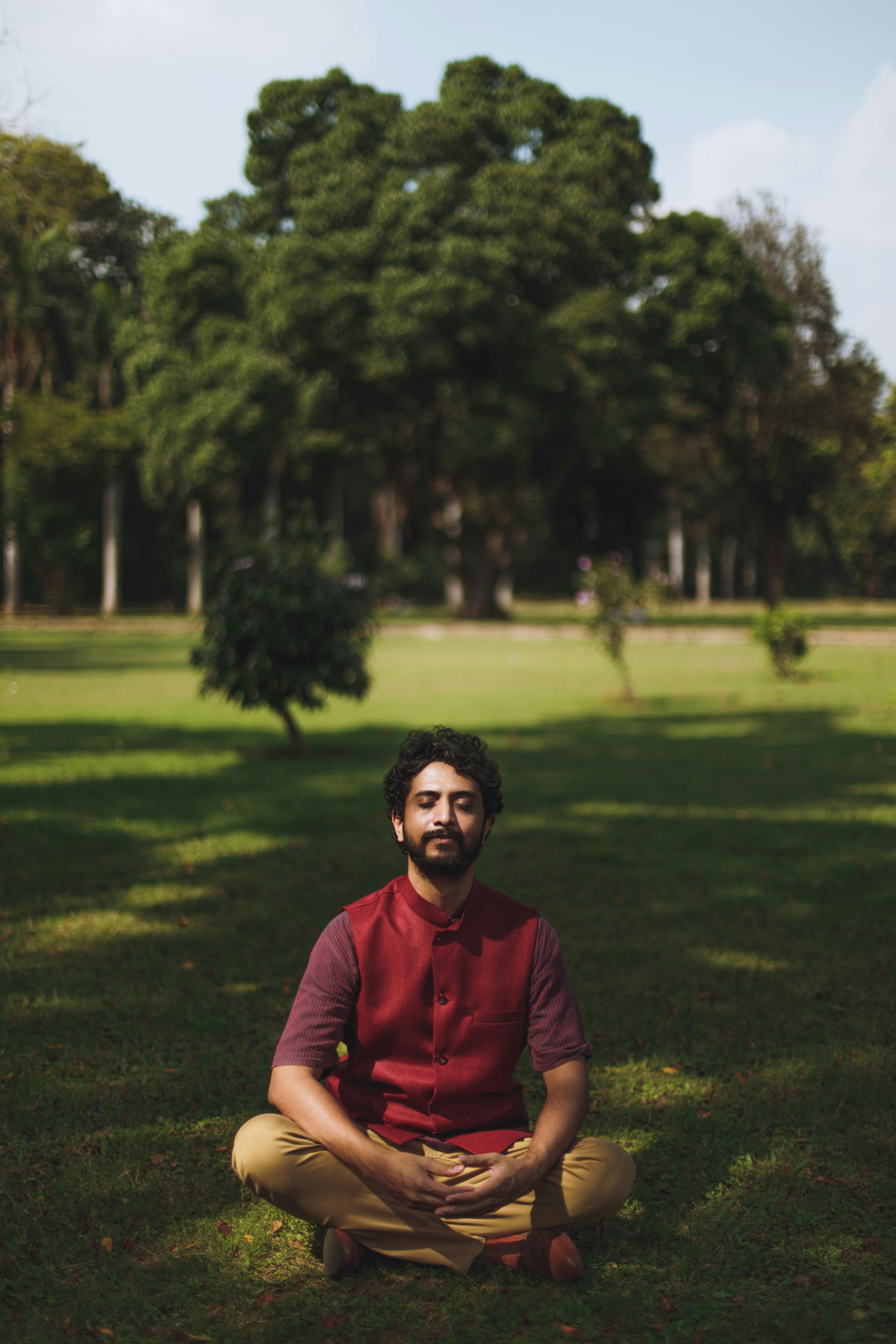 Man in Red Polo Shirt Sitting on Green Grass Field \u00b7 Free Stock Photo