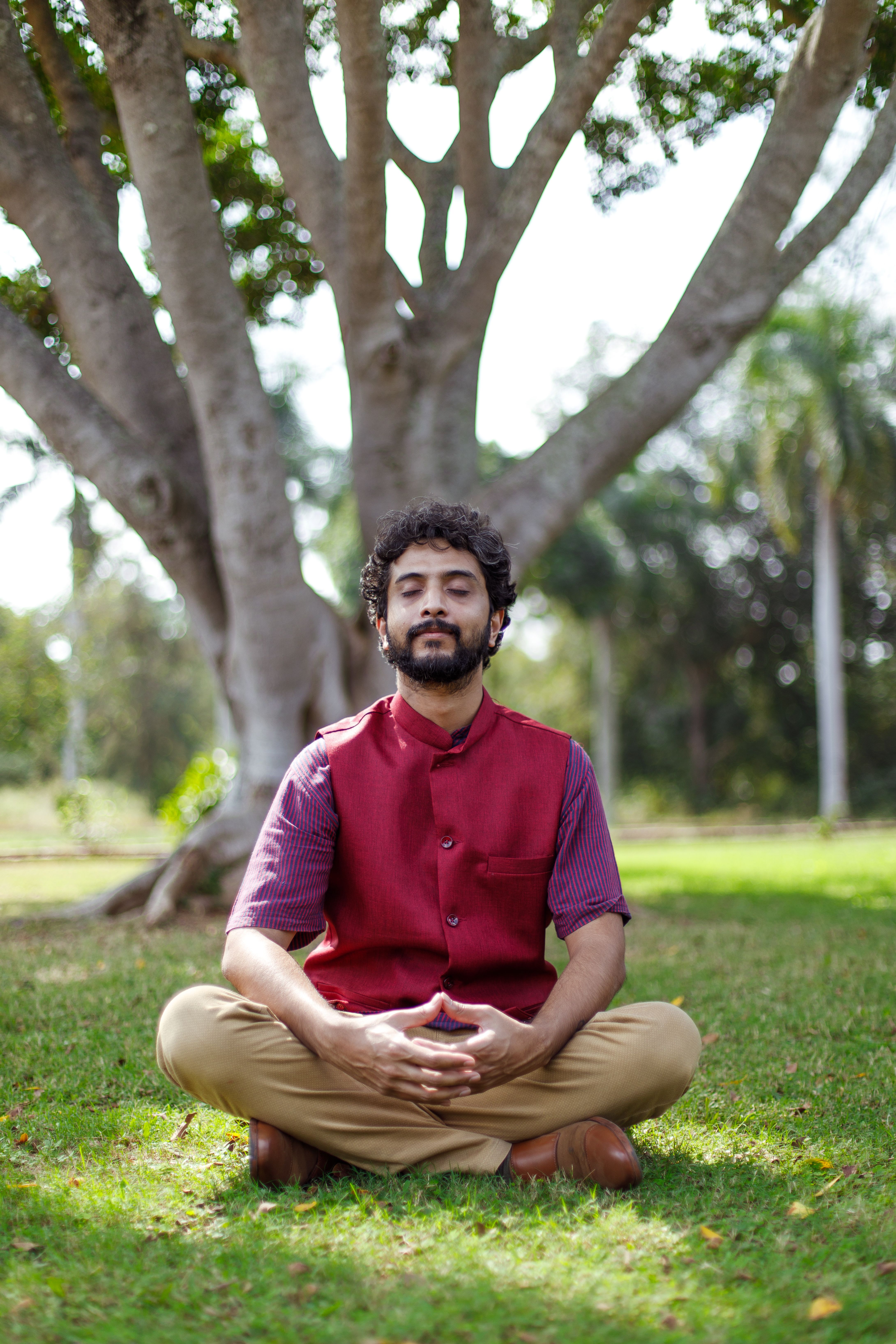 A man meditates in a yoga position outdoors in an Adelaide park, promoting peace and mindfulness.