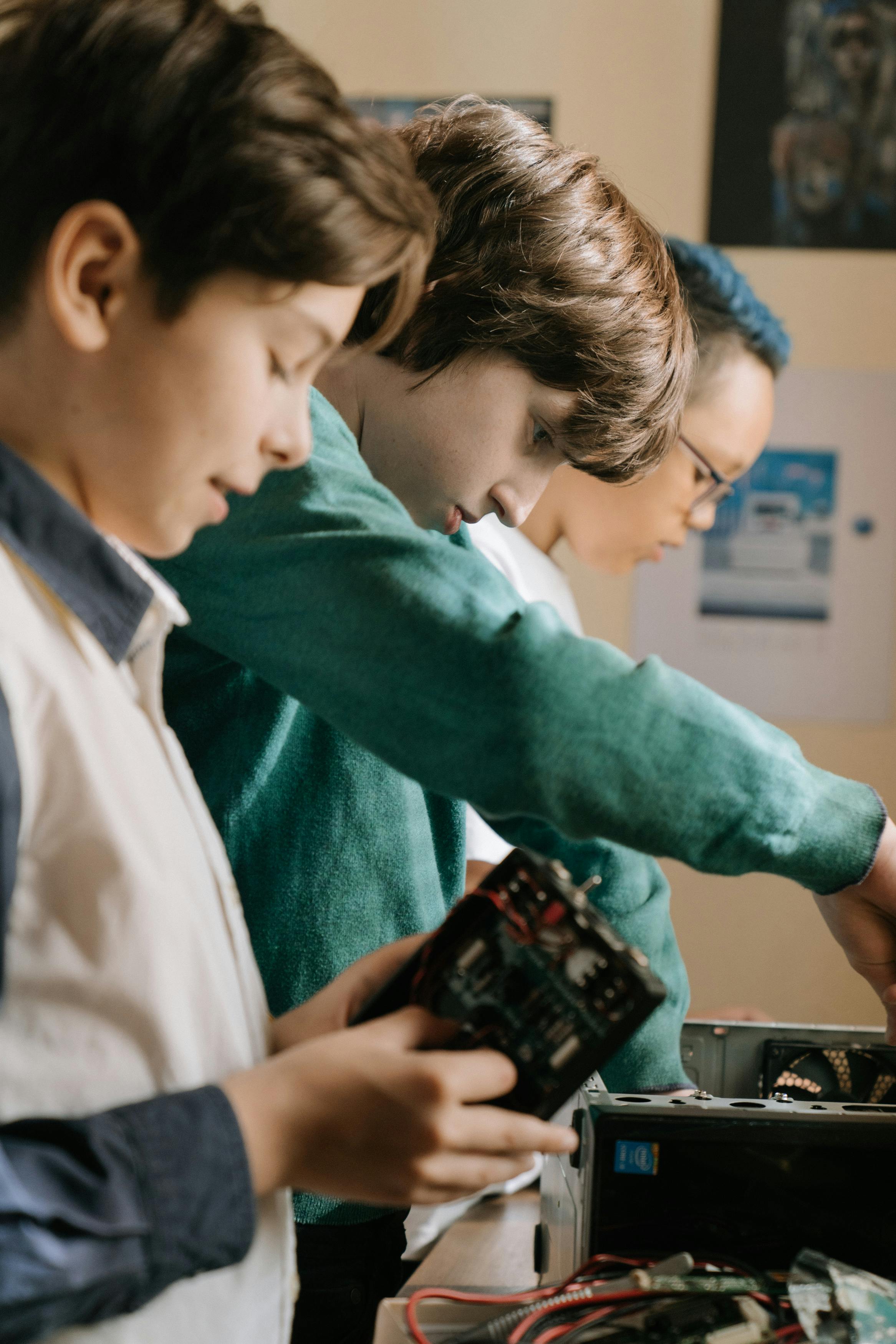 Young kids collaborating on a DIY computer project indoors. Tech skills and teamwork.