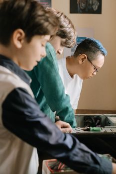 三个少年在室内全神贯注地组装电脑部件