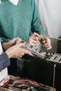 特写镜头聚焦于技术人员用工具修理计算机硬件，重点在于手和设备