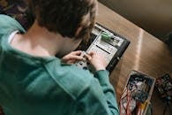 Boy in Green Sweater Playing With White and Black Game Controller