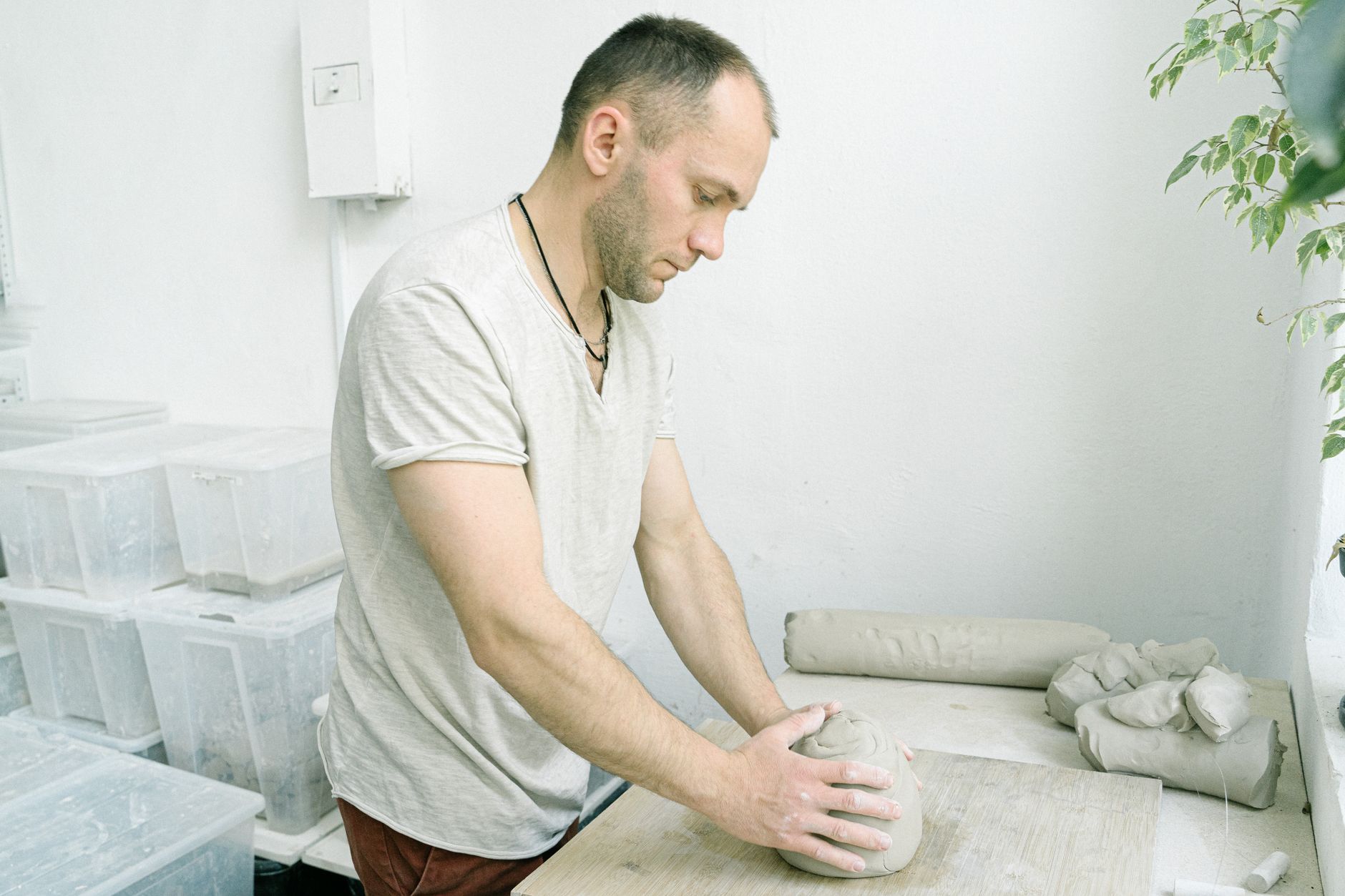 Man crafting pottery in a studio, highlighting traditional clay molding techniques.