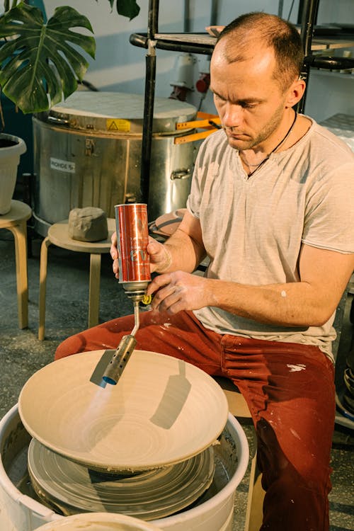 Man Drying A Clay Bowl With Blow Torch