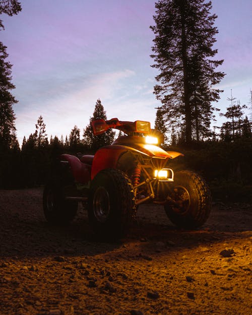 Red Quad Bike on Dirt Road With Headlights On