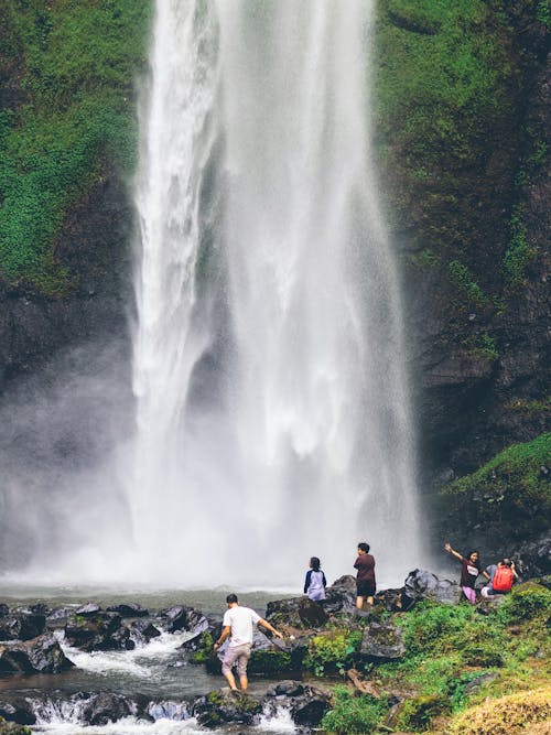 People Standing on Rocks Near Waterfalls