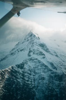 A breathtaking aerial view of a snow-covered mountain peak in winter, captured in Queenstown, New Zealand.