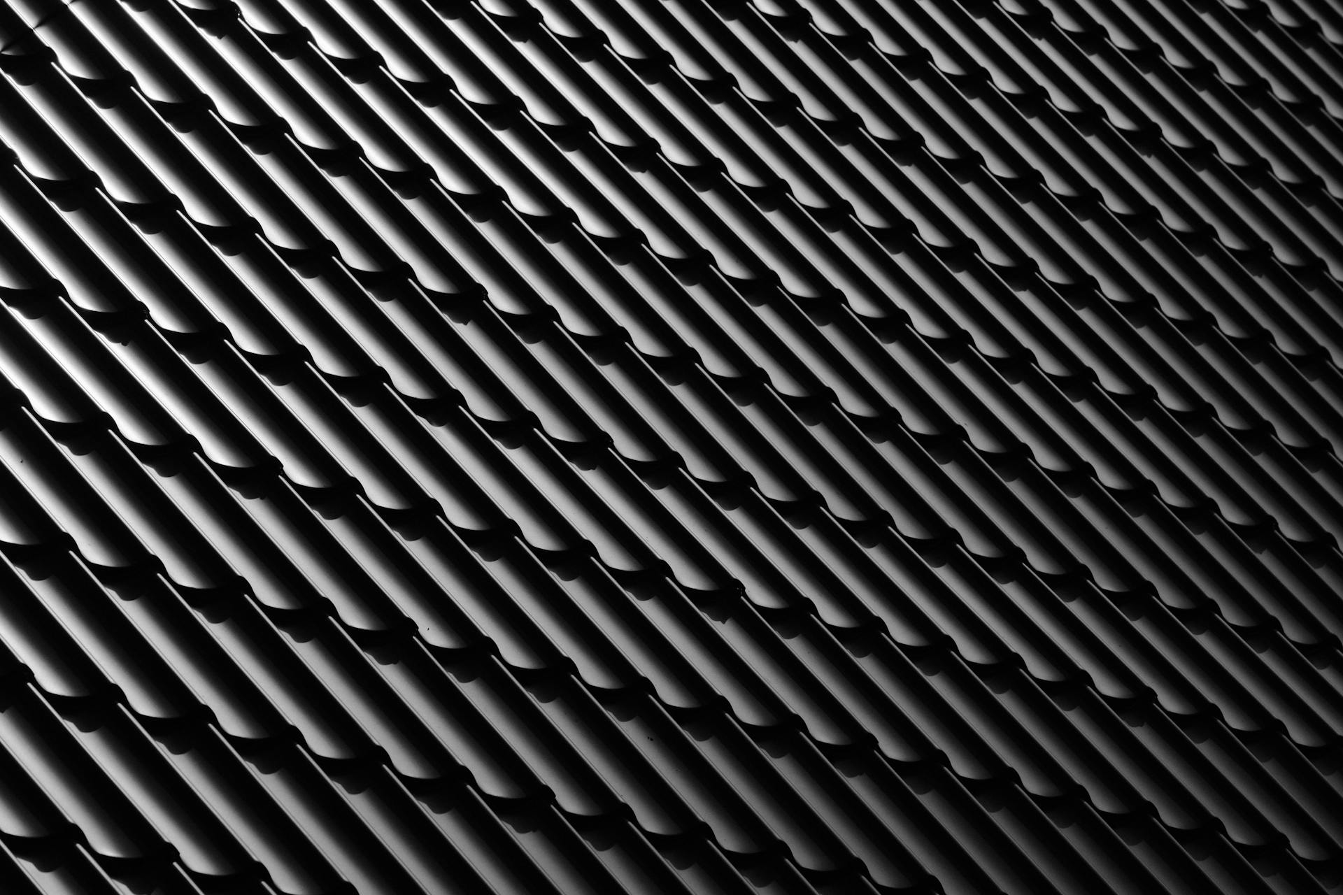 Abstract monochrome image featuring a sleek black tile roof with distinct patterns and shadows.