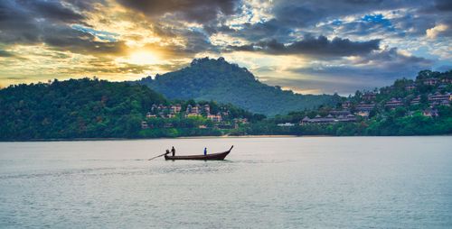 Free A serene view of a long-tail boat on Krabi's waters at sunset, highlighting lush landscapes. Stock Photo