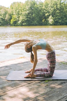 阳光明媚，一名女子在风景优美的湖边码头上练习瑜伽，拥抱自然与正念