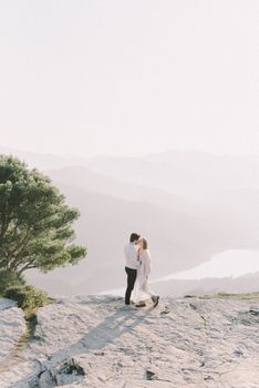 一对夫妇在山顶欣赏着宁静的山谷景色，共享着温柔的时刻