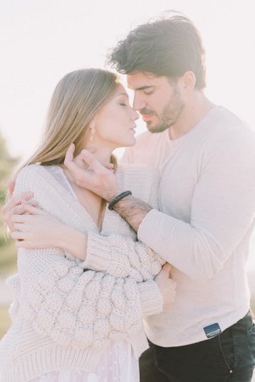 Hombre En Suéter Gris Besando A Mujer En Suéter De Punto Blanco
