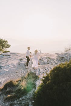 日落时分，一对夫妇手牵着手，快乐地走在崎岖的山路上