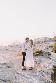 在柔和的日光下，一对夫妇相拥于岩石景观之上，展现了爱与自然的交融