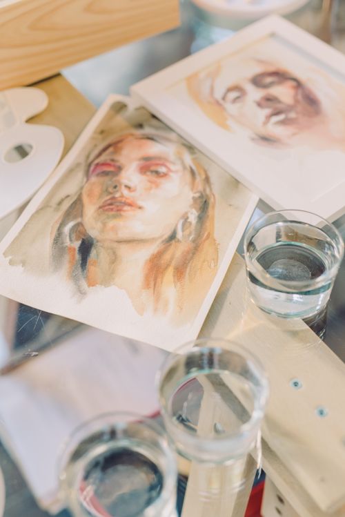 Free A collection of artistic watercolor portraits showcasing vibrant creativity on a glass table. Stock Photo