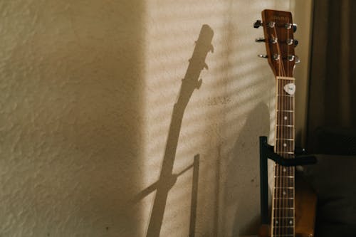 Free Brown Acoustic Guitar on White Textile Stock Photo