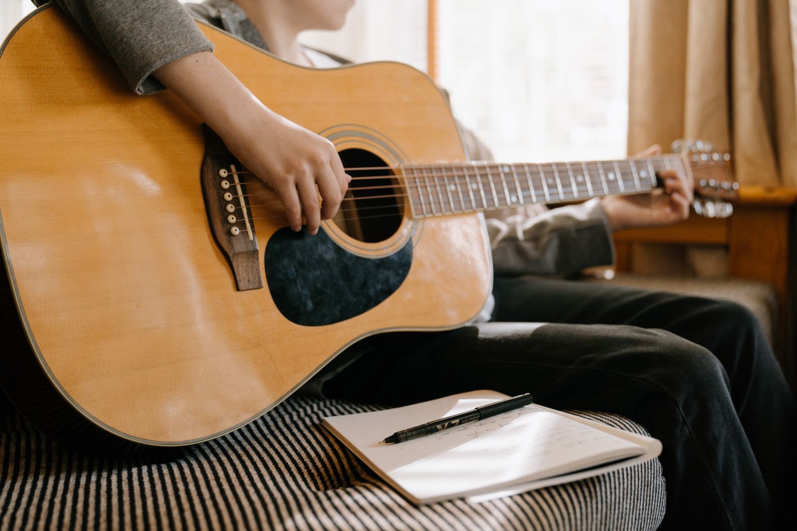 Songwriter with an acoustic guitar and a notebook