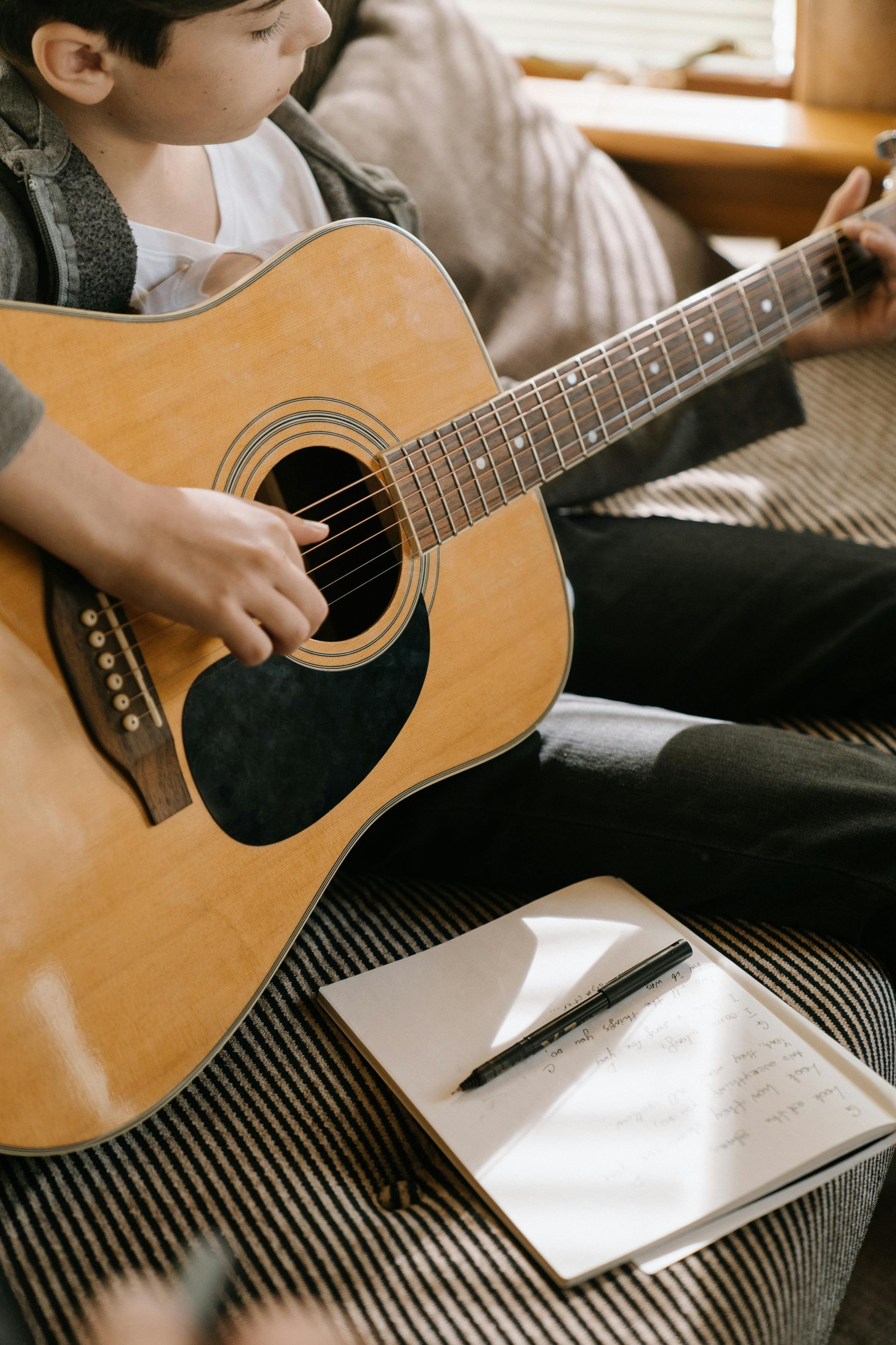 person holding brown acoustic guitar