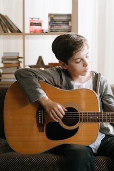 Child playing acoustic guitar indoors, showcasing musical talent and leisure activity.