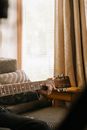 Brown and Black Acoustic Guitar on Gray and White Striped Sofa