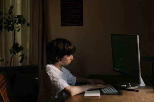 Teenage boy focused on coding at home, using a desktop computer. Perfect for technology themes.