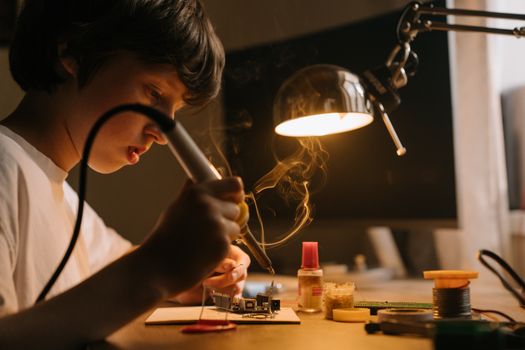 孩子在车间里专心用工具焊接电子电路板
