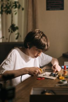 一个小男孩正专注地在桌子上用各种电子工具焊接印刷电路板