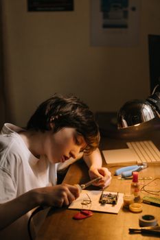 一个男孩正全神贯注地用桌上的烙铁修复电路板