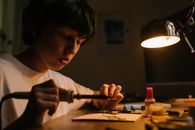 青少年在台灯下专注地焊接电路板