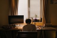 一个年轻人在井然有序的家庭办公桌前，专注地焊接着他的电子元件