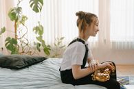 Woman in White T-shirt and Black Pants Sitting on Bed