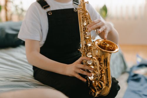 Free A young musician playing the saxophone indoors, focusing on musical expression. Stock Photo