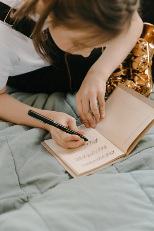 Woman in White Shirt Holding Pen Writing on White Paper