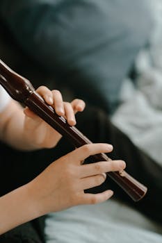 Hands delicately playing a wooden flute, focusing on the art of music making.