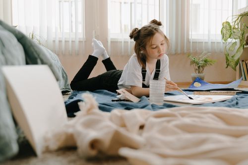 Free Young girl painting on floor in a cozy room, embodying creativity and leisure. Stock Photo