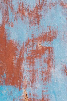 特写镜头对准一堵质朴、有纹理的墙壁，上面有剥落的油漆和铁锈的细节