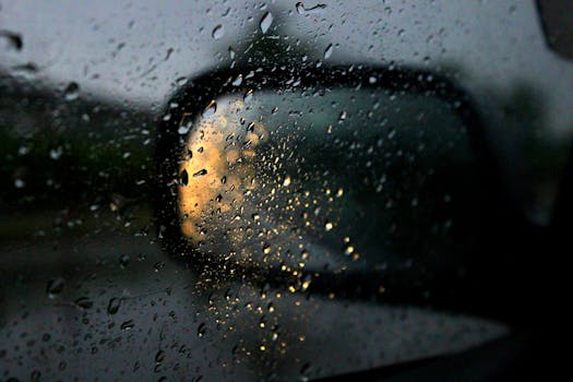 城市灯光在水滴上的特写，映在夜间汽车的镜子上