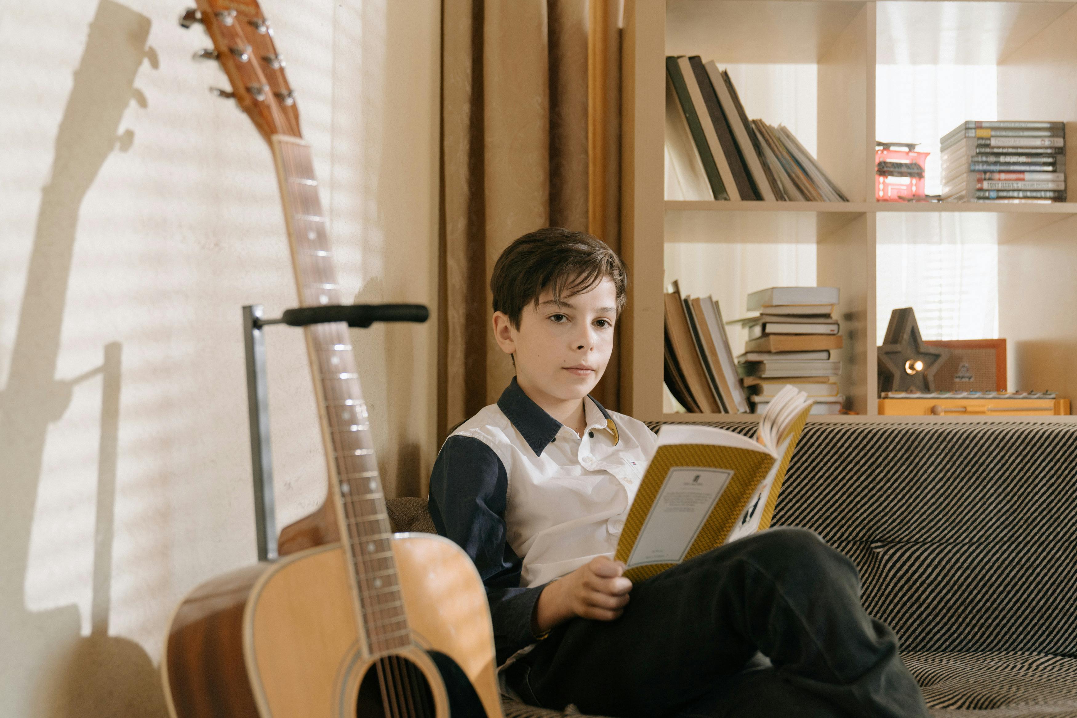 boy in black vest playing brown acoustic guitar