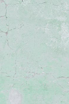 特写镜头下，绿色石膏墙的破裂纹理清晰可见，细节丰富，尽显岁月痕迹