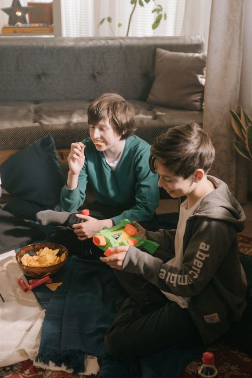 Free Two boys playing with water guns and enjoying snacks inside a cozy living room. Stock Photo