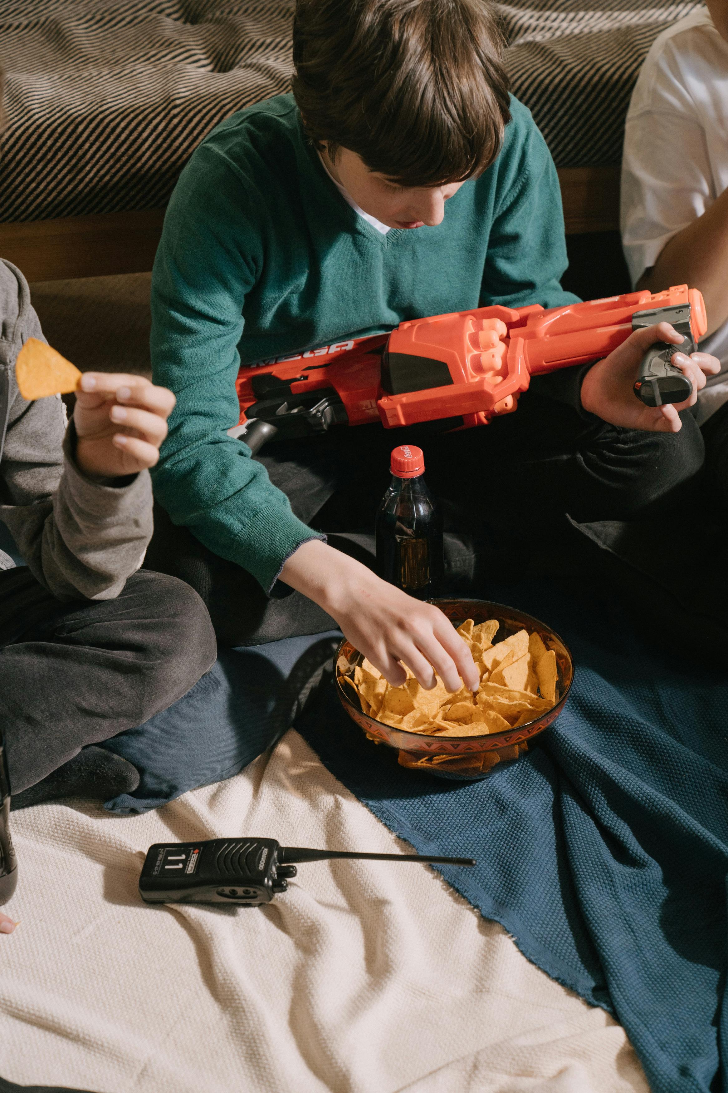 Man in Green Sweater Holding Red and Black Toy Gun · Free Stock Photo