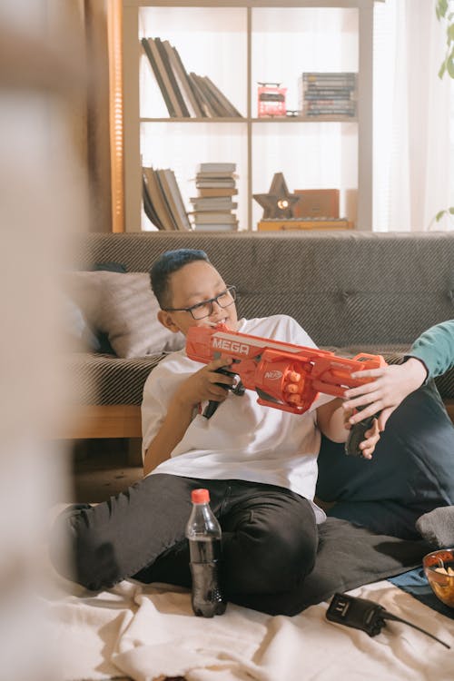 Man in Gray Crew Neck T-shirt Holding Red Plastic Toy