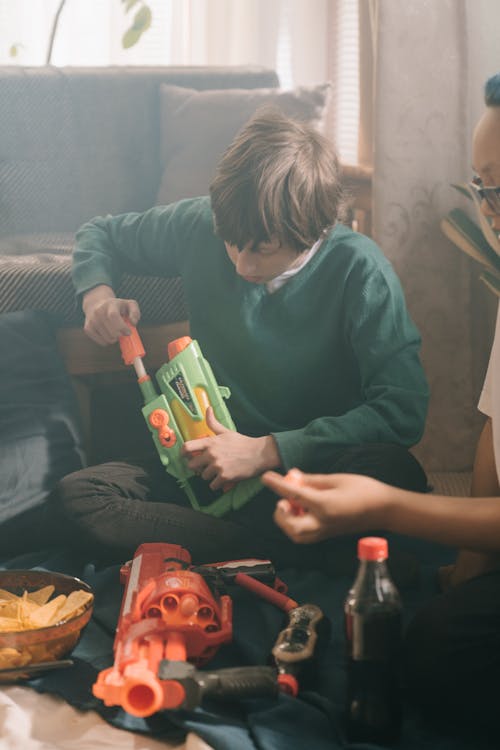 Boy in Green Crew Neck Long Sleeve Shirt Holding Red and White Box