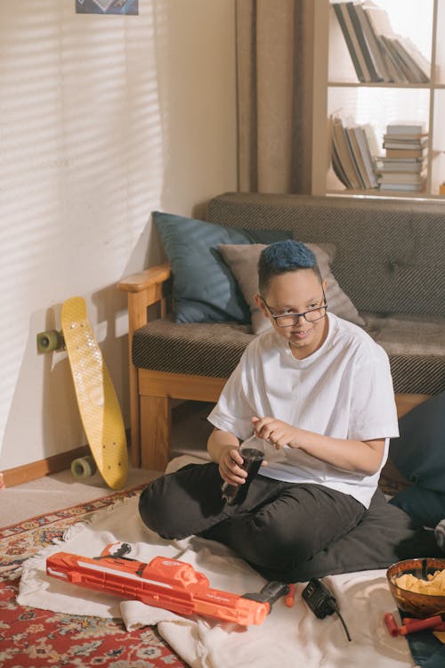 Man in White Crew Neck T-shirt Sitting on Gray Sofa