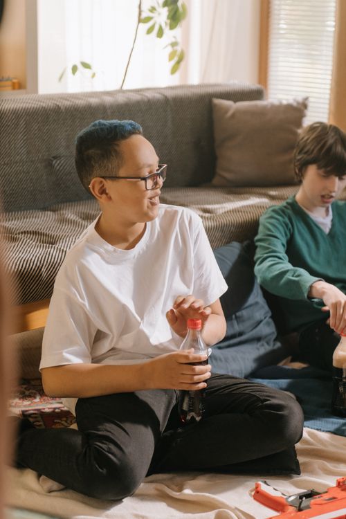 Free Two children enjoying leisure time indoors with toys and soda, engaging in playful activities. Stock Photo