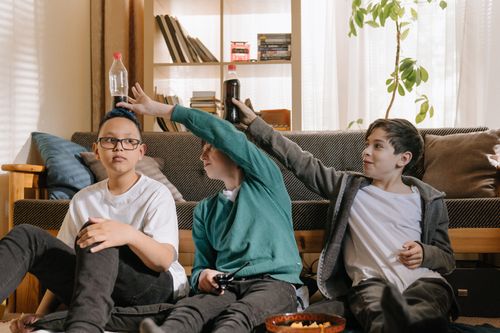 Free Three kids having fun indoors, balancing soda bottles. A fun and playful indoor activity. Stock Photo
