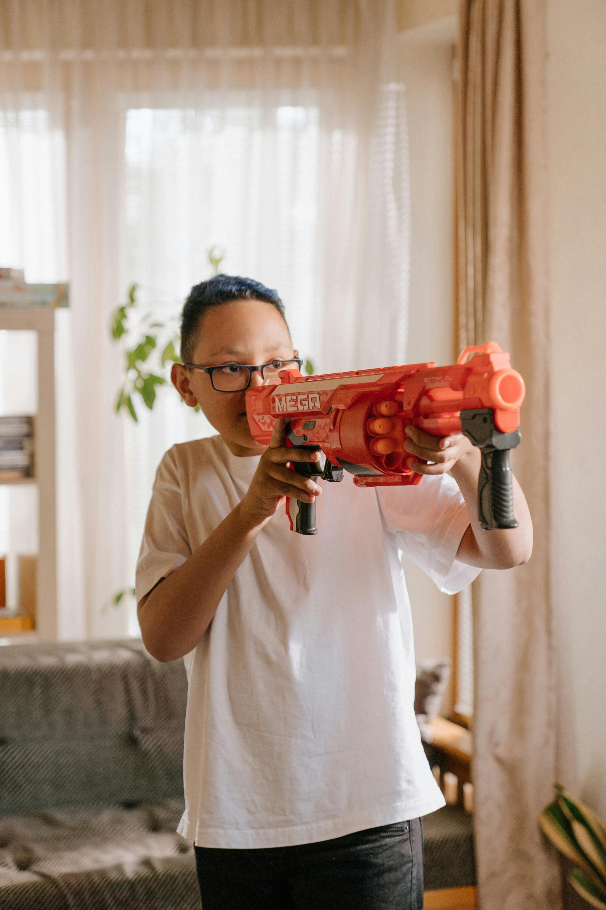 man in white crew neck t shirt holding red and black toy gun