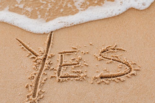 A Yes Word Written on Beach Sand