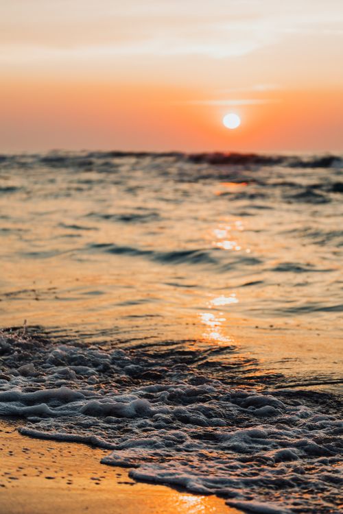 Free Capture of a beautiful sunset over the sea with waves crashing on Karwia Beach, Poland. Stock Photo